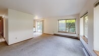 Located at 314 N 134th St in Seattle, WA, this single-floor, two-bedroom, one-bathroom unit offers a practical and well-organized layout. The combined kitchen and living room serves as the heart of the home, with the living area featuring wall-to-wall carpeting, baseboard heating, and multiple large windows that frame lush greenery and garden views, filling the space with natural light. A sliding glass door provides direct outdoor access, enhancing the connection to the surrounding landscape.

The kitchen is designed for functionality, featuring light gray cabinetry with ample upper and lower storage, gray laminate countertops, tile flooring, and a full suite of white appliances including a refrigerator, electric range with overhead ventilation, and dishwasher. A dedicated sink area adds convenience to daily use.

Both bedrooms are carpeted and offer sliding closet doors for storage. The primary bedroom includes a double closet configuration, while the second bedroom features a window overlooking the greenery outside, along with its own baseboard heating. Each bedroom benefits from a quiet, comfortable atmosphere.

The bathroom includes a vanity with gray countertops, an undermount sink, tile flooring, and a closet with sliding doors just outside, providing additional storage. Throughout the unit, warm wood-toned door accents and neutral walls create a cohesive, understated aesthetic.