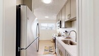 Located at 544 Central Ave in Alameda, California, this well-appointed one-bedroom, one-bathroom residence offers a thoughtfully designed single-floor layout. Light-toned luxury vinyl plank flooring flows throughout the main living areas, complemented by a neutral color palette and textured ceilings that give the space a clean, modern feel.

The living room is generously proportioned and bathed in natural light, featuring a sliding glass door that opens to a private balcony with views of surrounding trees — a standout feature that seamlessly blends indoor and outdoor living. The open sightlines connect the living area to a dedicated dining space and the galley-style kitchen beyond.

The kitchen is efficiently designed with warm taupe cabinetry, quartz countertops, a stainless steel sink, and a full suite of stainless steel appliances including a refrigerator, range, and built-in microwave. Upper and lower cabinetry provides ample storage, while a window at the far end draws in additional natural light.

The bedroom is a comfortable, carpeted retreat with a wide horizontal window, offering a quiet and restful atmosphere. A dedicated closet provides convenient storage. The space also includes an in-unit washer with a built-in countertop surround, adding exceptional practicality to this centrally located Alameda residence.