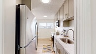 Located at 544 Central Ave in Alameda, California, this well-appointed one-bedroom, one-bathroom residence offers a thoughtfully designed single-floor layout. Light-toned luxury vinyl plank flooring flows throughout the main living areas, complemented by a neutral color palette and textured ceilings that give the space a clean, modern feel.

The living room is generously proportioned and bathed in natural light, featuring a sliding glass door that opens to a private balcony with views of surrounding trees — a standout feature that seamlessly blends indoor and outdoor living. The open sightlines connect the living area to a dedicated dining space and the galley-style kitchen beyond.

The kitchen is efficiently designed with warm taupe cabinetry, quartz countertops, a stainless steel sink, and a full suite of stainless steel appliances including a refrigerator, range, and built-in microwave. Upper and lower cabinetry provides ample storage, while a window at the far end draws in additional natural light.

The bedroom is a comfortable, carpeted retreat with a wide horizontal window, offering a quiet and restful atmosphere. A dedicated closet provides convenient storage. The space also includes an in-unit washer with a built-in countertop surround, adding exceptional practicality to this centrally located Alameda residence.