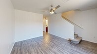Located at 8610 N 91st Ave in Peoria, Arizona, this two-story, 3-bedroom, 3-bathroom home offers a well-organized layout across two floors. The main level features a bright, open living room with wood-look laminate flooring, a ceiling fan with light fixture, and a large window that fills the space with natural light. The adjacent kitchen is equipped with rich warm-toned cabinetry, a double sink, white appliances including a range, microwave, and dishwasher, and a light-colored countertop — all complemented by matching wood-look flooring. A staircase leads to the upper level, where the bedrooms are located. Each bedroom is carpeted and features ceiling fans and large windows that bring in plenty of natural light and outdoor views. The primary bedroom includes a mirrored sliding closet door. The hallway on the upper floor connects all bedrooms and bathrooms with clean, consistent wood-look flooring throughout. The three bathrooms are consistently appointed with warm wood-toned vanity cabinetry, gray countertops, and tub/shower combinations. The overall aesthetic is clean and neutral, with white walls throughout creating a bright and functional living environment.