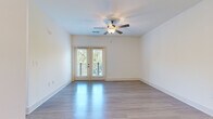 Located in Charlotte, NC, this well-designed single-floor residence on Vandelay Court offers a clean, modern aesthetic throughout. The open living area features light-toned hardwood-style flooring that reflects natural light beautifully, a ceiling fan, and a set of French doors that open to a private balcony overlooking lush greenery — creating a bright and airy atmosphere.

The kitchen is a standout feature, appointed with crisp white cabinetry extending to the ceiling for ample storage, granite countertops with subtle veining, a subway tile backsplash, and a full suite of stainless steel appliances including a range, microwave, dishwasher, and refrigerator. Pendant lighting and recessed fixtures illuminate the space, while a central island with a double sink adds both functionality and style.

The bedrooms are carpeted for comfort and each receives generous natural light through large windows with outdoor views. Ceiling fans are present in multiple rooms. The primary bathroom features an extended granite-topped vanity with white cabinetry, hardwood-style flooring, and access to a walk-in closet and a separate bathing area. Additional rooms with light hardwood-style flooring offer flexible use as a dining or flex space. The overall palette of soft whites and neutrals lends the entire residence a clean, contemporary feel.