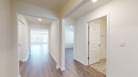 This single-floor home presents a clean, modern aesthetic throughout its well-designed layout. The interior is unified by warm wood-look hardwood flooring that flows through the main living areas, hallways, and bedrooms, while neutral cream-toned walls create a bright, welcoming atmosphere.

The kitchen is a functional highlight, featuring white cabinetry, granite countertops, and a full suite of stainless steel appliances including a French door refrigerator, electric range, and over-the-range microwave. Recessed lighting illuminates the space effectively.

The expansive main living area benefits from multiple windows and a glass-panel exterior door, allowing generous natural light and outdoor views. A ceiling fan with integrated lighting fixture serves the secondary living or dining space, which also features a large window with blinds.

Bedrooms are well-proportioned with neutral finishes, wood-look flooring, and windows providing natural light and ventilation. The bathrooms include stone-look tile flooring, white vanities with solid countertops, and a full tub-shower combination. A dedicated laundry room accommodates a full-size washer and dryer with wire shelving above for additional storage.

The overall design is cohesive, practical, and move-in ready.