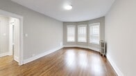 Located on W Fargo Ave in Chicago's West Rogers Park neighborhood, this 3-bedroom, 1-bathroom unit offers a well-organized single-floor layout with a clean, updated aesthetic throughout. Rich hardwood floors run consistently across the living areas and bedrooms, complementing the neutral gray walls and crisp white trim that give the space a bright, cohesive feel.

The spacious primary bedroom stands out with a graceful curved bay window featuring three panes that invite ample natural light, along with a classic cast-iron radiator that adds a touch of vintage Chicago charm. The two additional bedrooms are well-proportioned, each with windows fitted with blinds and their own radiators for individual comfort. One bedroom also features a built-in double closet with paneled doors, providing generous storage.

The hallways connect the rooms efficiently, with arched and paneled doorways adding subtle architectural character. The kitchen is cleanly finished with white shaker-style cabinetry, a white quartz countertop, a stainless steel sink, and wood-look flooring — practical and polished. The bathroom features full-height subway-style tile surrounding a soaking tub and shower combo, with a privacy window allowing natural light. The overall ambiance is tidy, functional, and move-in ready.
