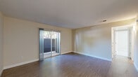Located at 7799 Farmgate Way in Citrus Heights, California, this two-bedroom, one-bathroom unit offers a practical and comfortable single-floor layout. The living room is bright and open, featuring wood-look vinyl flooring and a sliding glass door that leads to an outdoor patio, filling the space with natural light and providing outdoor access. The kitchen flows directly from the living area and is equipped with dark brown cabinetry, granite-look countertops, a full suite of white appliances including a refrigerator, electric range, microwave, and dishwasher, plus light vinyl plank flooring and a ceiling fan overhead. A hallway connects the living spaces to the two bedrooms and bathroom. The primary bedroom is a comfortable size, featuring plush carpeting, a large sliding-door closet, and a window with outdoor views. The second bedroom, also carpeted, includes a window that allows natural light to filter in. The full bathroom is neatly appointed with wood-look tile flooring, a single-sink dark-toned vanity with a matching countertop, and a full tub and shower combo. Neutral warm-beige walls, white trim, and consistent flooring choices throughout give the unit a clean, cohesive aesthetic.