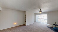 This single-story, one-bedroom, one-bathroom residence in Houston, TX offers a thoughtfully designed layout across a comfortable footprint. The living area is carpeted and features a ceiling fan with light fixture, a textured ceiling, and a built-in wall shelving unit ideal for display or storage. A large sliding glass door floods the space with natural light and provides direct access to an outdoor balcony, offering views of the surrounding area through vertical blinds.

The entryway transitions from dark wood-style vinyl plank flooring to carpet, clearly delineating the entry from the main living space. The kitchen is well-equipped with white upper cabinetry, blue-grey lower cabinets, a white tile backsplash, light countertops, a double stainless steel sink, a black electric range, and a stainless steel dishwasher. The bedroom features the same dark wood-style vinyl plank flooring, a flush-mount ceiling light, and a connecting hallway leading toward the bathroom. The bathroom includes a shower-tub combination with dark hardwood-style flooring. Throughout, the unit maintains a neutral, light-toned palette, contributing to a clean and bright overall ambiance.