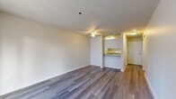 This one-bedroom, one-bathroom unit at 1111 47th St SE, Unit 207, in Everett, WA offers a well-organized layout across a single floor. The open-concept living and dining area is finished with wood-style laminate flooring and a ceiling fan, creating a bright and functional space. A sliding glass door leads to a private balcony, bringing in natural light and outdoor views. The galley-style kitchen features white cabinetry, granite-look countertops, a stainless steel sink, and white appliances including a range and refrigerator, with a pass-through counter that opens to the living area. The bedroom is a comfortable size, carpeted, and equipped with a sliding-door closet and a window that provides natural light. The bathroom includes a white vanity with granite-look countertops, a large mirror, and wood-style flooring. A dedicated in-unit laundry area houses a stacked washer and dryer. Throughout the unit, textured ceilings and baseboard heating are consistent features. The hallway connects all rooms efficiently, contributing to the unit's practical and cohesive design.