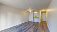 This one-bedroom, one-bathroom unit at 1111 47th St SE, Unit 207, in Everett, WA offers a well-organized layout across a single floor. The open-concept living and dining area is finished with wood-style laminate flooring and a ceiling fan, creating a bright and functional space. A sliding glass door leads to a private balcony, bringing in natural light and outdoor views. The galley-style kitchen features white cabinetry, granite-look countertops, a stainless steel sink, and white appliances including a range and refrigerator, with a pass-through counter that opens to the living area. The bedroom is a comfortable size, carpeted, and equipped with a sliding-door closet and a window that provides natural light. The bathroom includes a white vanity with granite-look countertops, a large mirror, and wood-style flooring. A dedicated in-unit laundry area houses a stacked washer and dryer. Throughout the unit, textured ceilings and baseboard heating are consistent features. The hallway connects all rooms efficiently, contributing to the unit's practical and cohesive design.