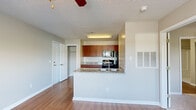 Located at 511 Cobblestone Dr in Wilmington, NC, this single-floor residence offers a well-designed, functional layout with consistent finishes throughout. The kitchen is a standout feature, showcasing rich warm-toned cabinetry, granite countertops, and black appliances including a range, built-in microwave, refrigerator, and dishwasher. A peninsula with an integrated sink and additional granite counter space provides both extra prep area and a natural divide between the kitchen and the living area. The living room is bright and welcoming, benefiting from a large window that brings in natural light and offers outdoor views of the surrounding greenery. A ceiling fan adds both style and practicality to the space. Hardwood-style flooring runs throughout the main living areas, creating a cohesive and easy-to-maintain surface. The bedroom connects to additional spaces and features neutral tones with carpet and a thermostat for personalized climate control. The bathroom is appointed with a dark granite vanity top, warm wood cabinetry, a framed mirror, and a well-lit vanity light bar. A textured ceiling is present throughout, adding subtle architectural character. Overall, the space presents a clean, neutral palette ideal for comfortable everyday living.
