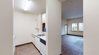 Located at 815 NW Naito Parkway in Portland's vibrant Pearl District-adjacent waterfront corridor, this single-floor unit offers a functional and thoughtfully arranged layout. The galley-style kitchen features white cabinetry with warm wood-tone trim, white laminate countertops, a built-in dishwasher, electric range, and a pass-through window that connects to the living area, promoting an open and communicative feel. The living area is finished with rich, dark hardwood-style flooring and benefits from natural light streaming in through a glass-paned entry door. A pass-through to the kitchen adds visual openness to the space. The bedrooms are carpeted for comfort and feature large windows that invite natural light and views of the surrounding greenery, along with elevated ceilings that add a sense of airiness. Two full bathrooms are included, each featuring a tub/shower combination, wood-tone vanity cabinetry, white countertops, and hardwood-style flooring that ties in with the rest of the unit. Warm neutral tones and wood accents throughout create a cohesive and inviting atmosphere, while the practical layout ensures efficient use of every area in this well-appointed Portland residence.