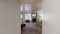 Located in Oro Valley, Arizona, this single-story residence offers a well-organized, functional layout designed for comfortable living. The spacious living room serves as the heart of the home, featuring plush carpeting, a tile-surround fireplace, and large windows that allow abundant natural light to fill the space. A dedicated seating area flows naturally from the main living space, providing flexibility for various furniture arrangements. The dining area is highlighted by hardwood-style flooring, a ceiling fan with light fixture, and a sliding glass door dressed with vertical blinds that opens to the outdoors. The galley-style kitchen is equipped with wood cabinetry, light countertops, a full suite of white appliances including a range and over-the-range microwave, and easy-care hardwood-style flooring. The home includes two well-proportioned bedrooms, each with soft carpeting and windows offering outdoor views. The primary bedroom features a walk-in closet and direct access to a private bathroom. The bathrooms are finished with warm wood cabinetry, light countertops, and hardwood-style flooring. One bathroom includes a stand-up shower with sliding glass doors. Throughout, the home maintains a neutral, light-toned palette that creates a cohesive and inviting atmosphere.