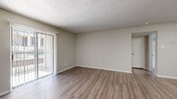 Located in Austin, TX (78753), this single-floor, one-bedroom, one-bathroom unit offers a functional and well-organized layout. The combined kitchen and living room serves as the heart of the home, featuring wood-style laminate flooring, neutral gray walls, and a textured ceiling. The living area is bathed in natural light through a sliding glass door fitted with vertical blinds, which opens to an outdoor balcony with exterior views. The galley-style kitchen is efficiently designed with warm wood cabinetry lining both sides, light-toned countertops, and black appliances including a range, dishwasher, and over-the-range microwave. A peninsula provides a natural boundary between the kitchen and living spaces. The bedroom is a comfortable, carpeted retreat equipped with a ceiling fan and light fixture, a window for natural light, and direct access to a walk-in closet outfitted with built-in shelving and hanging rods. The bathroom includes a full tub-shower combination, a toilet, a vanity, and warm wood-toned upper cabinetry for storage. Throughout the unit, consistent wood-style flooring in common areas and plush carpet in the bedroom contribute to a cohesive and practical interior finish.