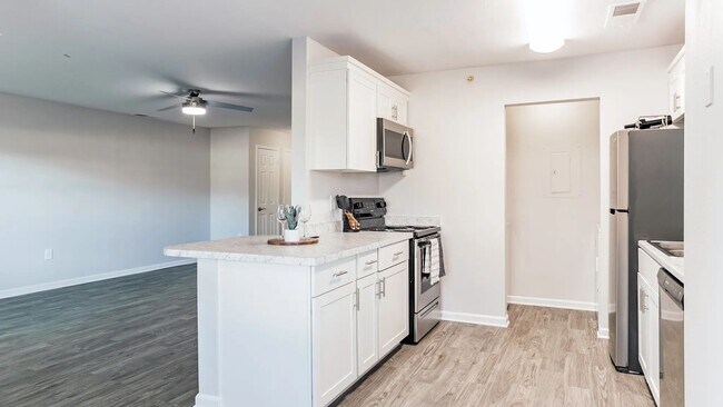 Descubra un oasis culinario en nuestro plano de planta de un dormitorio con cocina estilo cocina. Las encimeras de granito y los electrodomésticos de acero inoxidable mejoran su experiencia culinaria. - Market 1900 Apartment Homes