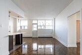 Located at 1080 Kingston Rd in Toronto's Upper Beaches neighbourhood, this 2-bedroom, 1-bathroom unit offers a practical and well-appointed layout across a single floor. The living room is a standout feature, offering generous open space highlighted by gleaming parquet wood flooring that flows throughout the main living areas. Large windows flood the space with natural light and frame views of the surrounding urban streetscape.

The galley-style kitchen is efficiently designed, featuring dark espresso cabinetry extending to the ceiling for ample storage, light stone countertops, white subway tile backsplash, stainless steel appliances, and neutral tile flooring. A structural column subtly separates the kitchen from the living area, adding architectural character.

Both bedrooms continue the parquet flooring theme and are bright, with large windows and baseboard heating units. The primary bedroom offers a comfortable footprint suited for a full bedroom setup, while the second bedroom provides flexibility as a guest room or home office.

The bathroom is finished with neutral large-format wall tiles, a soaker tub with integrated shower, chrome fixtures, a safety grab bar, and a quartz vanity countertop. A hallway connects all rooms, contributing to a logical and functional flow throughout the unit.