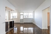 Located at 1080 Kingston Rd in Toronto's Upper Beaches neighbourhood, this 2-bedroom, 1-bathroom unit offers a practical and well-appointed layout across a single floor. The living room is a standout feature, offering generous open space highlighted by gleaming parquet wood flooring that flows throughout the main living areas. Large windows flood the space with natural light and frame views of the surrounding urban streetscape.

The galley-style kitchen is efficiently designed, featuring dark espresso cabinetry extending to the ceiling for ample storage, light stone countertops, white subway tile backsplash, stainless steel appliances, and neutral tile flooring. A structural column subtly separates the kitchen from the living area, adding architectural character.

Both bedrooms continue the parquet flooring theme and are bright, with large windows and baseboard heating units. The primary bedroom offers a comfortable footprint suited for a full bedroom setup, while the second bedroom provides flexibility as a guest room or home office.

The bathroom is finished with neutral large-format wall tiles, a soaker tub with integrated shower, chrome fixtures, a safety grab bar, and a quartz vanity countertop. A hallway connects all rooms, contributing to a logical and functional flow throughout the unit.