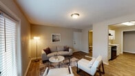 This single-story, 2-bedroom, 2-bathroom residence offers a thoughtfully designed layout that balances comfort and functionality. The living area serves as the heart of the home, featuring wood-look hardwood flooring, neutral warm-toned walls, and a textured ceiling. French doors allow natural light to fill the space, creating a bright and welcoming atmosphere. The room provides ample space for multiple seating arrangements, making it well-suited for both relaxing and entertaining.

Adjacent to the living area, the dining space features wood-look flooring that continues from the main living area, anchored by a pendant light fixture above a glass-top dining table. The galley-style kitchen is equipped with white shaker cabinetry, quartz countertops, a stainless steel sink, and black appliances, offering a clean and modern aesthetic with efficient use of space.

Both bedrooms are carpeted for added comfort and include ceiling fans with light fixtures and windows that provide natural light. The neutral color palette and clean lines maintain a cohesive, restful feel throughout. The bathrooms are practical in design, with wood-look tile flooring and tub-shower combinations. Overall, the unit presents a clean, modern interior with consistent finishes throughout.