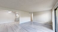 Located at 150 S Wood Ave in Oakdale, California, this single-floor unit offers a clean, neutral aesthetic throughout. Light-toned luxury vinyl plank flooring runs continuously across all living spaces, providing a cohesive and easy-to-maintain foundation. Textured popcorn ceilings and warm beige walls create a consistent backdrop in every room.

The open living area is generously proportioned, featuring multiple wall vents for climate control and a sliding glass door that opens to a private patio, allowing natural light to fill the space. An adjacent area offers additional flexibility for dining or secondary living use.

The galley-style kitchen is well-equipped with gray shaker cabinets lining both walls, light stone-pattern countertops, a stainless steel refrigerator, an electric range, a dishwasher, and recessed lighting overhead. A pass-through opening connects the kitchen visually to the main living area.

The bedroom areas include rooms with windows fitted with horizontal blinds, as well as spaces featuring dual six-panel doors leading to closets. Additional rooms provide versatile configurations suitable for sleeping or office use.

The unit's layout, as reflected in the dollhouse view, is compact yet functional, with well-defined zones for living, cooking, and sleeping — making it a practical and move-in ready space in a residential Oakdale neighborhood.