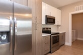 Located at 222 S Main St in Mooresville, NC, this well-appointed 2-bedroom, 2-bathroom residence offers comfortable single-floor living with a clean, modern aesthetic throughout. Light wood-look flooring flows seamlessly across the entire space, complemented by neutral warm-beige walls and crisp white trim that create a bright, cohesive atmosphere.

The open-concept kitchen serves as a central hub, featuring light wood cabinetry, stainless steel appliances, recessed lighting, and a center island with a white quartz countertop and pendant lighting—ideal for both cooking and casual dining. The kitchen connects openly to the living area, enhancing the sense of spaciousness.

The generously sized primary bedroom includes a ceiling fan, French doors that invite natural light, and access to outdoor views. The second bedroom benefits from tall windows with transom accents, filling the room with abundant natural light. Each bedroom is served by a dedicated closet with built-in wire shelving for organized storage.

Both bathrooms are finished with wood-toned vanities, quartz countertops, and brushed nickel hardware. One bathroom features a tub-shower combination with classic subway tile surround, while the other provides a refined vanity with a framed mirror. A dedicated laundry room with full-size washer and dryer and built-in shelving adds everyday convenience. A hallway connects all rooms efficiently, completing this thoughtfully designed residence.