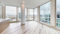 Located on Wilshire Boulevard in the heart of Los Angeles, this modern 2-bedroom, 2-bathroom residence offers a thoughtfully designed single-level layout with contemporary finishes throughout. Light wood-tone flooring flows seamlessly across every room, complementing the clean white walls and creating a bright, cohesive aesthetic.

The open-concept kitchen and living area is a standout feature, anchored by a sleek island with a warm wood base and white quartz countertop. The kitchen is outfitted with stainless steel appliances, white upper cabinetry, and a classic subway tile backsplash. Floor-to-ceiling wraparound windows in the living area flood the space with natural light and frame sweeping panoramic views of the Los Angeles skyline and surrounding cityscape.

The generously sized primary bedroom continues the floor-to-ceiling window theme, offering elevated city views and ample natural light. A walk-in closet and a well-appointed en-suite bathroom complete the primary suite, featuring warm wood cabinetry, a white quartz vanity, glass-enclosed shower, and direct access to a walk-in closet. The second bedroom includes sliding panel closet doors and large windows with city views. Both bathrooms mirror the home's modern design language with consistent wood and white finishes.