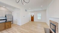 Located at 128 N Broadview St in Greenbrier, Arkansas, this two-story, 2-bedroom, 3-bathroom home is designed with a clean, modern aesthetic and a functional layout spread across two floors. Light wood luxury vinyl flooring flows consistently throughout, complementing the bright white walls and recessed lighting that give every room an open, airy feel. The main floor features an inviting living room anchored by a classic brick fireplace with a white mantel, bathed in natural light from multiple windows. A warm wood front door with glass accents welcomes you into the entry area. The kitchen is a standout, showcasing gray shaker-style cabinetry, dark granite countertops, stainless steel appliances, and a central island with a warm wood base — all beneath vaulted ceilings that add a sense of spaciousness. Upstairs, the generously sized primary bedroom features multiple windows for abundant natural light and includes a walk-in closet, accessed through a stylish sliding barn door. Additional bedrooms also offer closet space and bright windows with outdoor views. The three bathrooms are finished in a clean, contemporary style with white vanities and walk-in showers. Throughout the home, thoughtful details — from crown molding to brushed nickel fixtures — reflect quality craftsmanship.