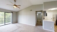 Located at 3205 E Olive Rd in Pensacola, FL, this single-floor, 2-bedroom, 2-bathroom home offers a well-organized layout with comfortable living spaces throughout. The open living room is a standout, featuring vaulted ceilings and a ceiling fan that enhance the sense of airiness, along with plush carpet flooring and a sliding glass door that opens to a private balcony with outdoor views. The kitchen is designed in a galley style with gray cabinetry, white countertops, a classic subway tile backsplash, wood-look vinyl flooring, and stainless steel appliances including a refrigerator, range, microwave, and dishwasher. A pass-through connects the kitchen to the living area, promoting an open feel. The primary bedroom is generously sized, featuring vaulted ceilings and a ceiling fan, complemented by soft carpet flooring and a dedicated closet. The second bedroom is equally well-appointed with a ceiling fan and carpeted floor. Both bathrooms are functional, with one featuring a full tub-shower combination with white tile surround. A dedicated laundry room with washer/dryer hookups and wood-look flooring adds everyday convenience. Two closets provide ample storage throughout the home.