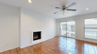 This single-floor residence offers a well-organized layout accommodating two bedrooms, two bathrooms, a living room, dining room, kitchen, hallway, entrance, and two closets. The living room serves as the centerpiece of the home, distinguished by a white-painted brick accent wall housing a wood-burning fireplace. Warm terracotta tile floors extend throughout the common areas, complemented by a ceiling fan and recessed lighting. A sliding glass door provides direct access to a private balcony, allowing natural light to fill the space. The kitchen features dark cabinetry, granite countertops, a stainless steel refrigerator, and a professional-style faucet at the sink, all set atop matching terracotta tile. The dining room continues the tile flooring and is lit by a flush-mount ceiling fixture. Both bedrooms transition to rich hardwood flooring and are equipped with ceiling fans. The primary bedroom includes an exterior door and window, offering additional natural light. The bathrooms are finished with light tile flooring, dark vanity cabinetry, granite countertops, and tub-shower combinations accented with decorative mosaic tile borders.