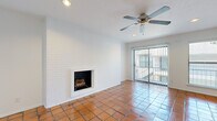 This single-floor residence offers a well-organized layout accommodating two bedrooms, two bathrooms, a living room, dining room, kitchen, hallway, entrance, and two closets. The living room serves as the centerpiece of the home, distinguished by a white-painted brick accent wall housing a wood-burning fireplace. Warm terracotta tile floors extend throughout the common areas, complemented by a ceiling fan and recessed lighting. A sliding glass door provides direct access to a private balcony, allowing natural light to fill the space. The kitchen features dark cabinetry, granite countertops, a stainless steel refrigerator, and a professional-style faucet at the sink, all set atop matching terracotta tile. The dining room continues the tile flooring and is lit by a flush-mount ceiling fixture. Both bedrooms transition to rich hardwood flooring and are equipped with ceiling fans. The primary bedroom includes an exterior door and window, offering additional natural light. The bathrooms are finished with light tile flooring, dark vanity cabinetry, granite countertops, and tub-shower combinations accented with decorative mosaic tile borders.