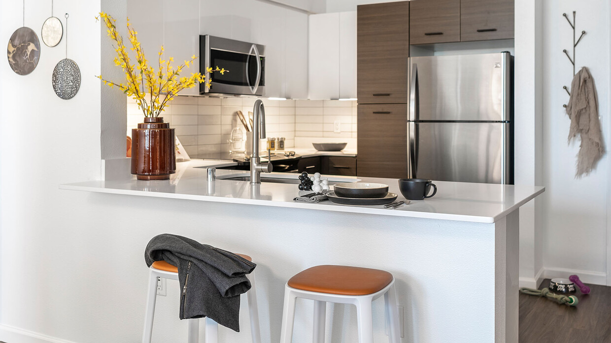 Cocina del apartamento con electrodomésticos de acero inoxidable, encimeras de cuarzo y pisos de madera. - Griffis Lake Washington