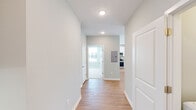 This single-story residence in Huntsville, Alabama presents a clean, contemporary design characterized by soft neutral tones, white trim, and an abundance of natural light throughout. The interior palette of light gray walls and white woodwork creates a cohesive, modern aesthetic from room to room.

The entry hallway, finished with smooth light-toned hardwood-style flooring and recessed lighting, connects the main living areas efficiently. The open-concept kitchen is a functional standout, featuring white shaker-style cabinetry, granite-look countertops, a peninsula with an undermount sink, and a full suite of stainless steel appliances including a refrigerator, range, and microwave. The kitchen flooring continues the warm hardwood-style finish seen throughout the main areas.

The living room benefits from multiple windows and a glass-paneled entry door with transom, flooding the space with natural light, while a ceiling fan adds comfort overhead.

Bedrooms are finished with plush neutral carpet and ceiling fans, each receiving natural light through blinded windows with exterior views.

The bathrooms are well-appointed, with one featuring a soaking tub with white subway tile surround, and another offering a glass-enclosed shower, both with granite-topped vanities and tile flooring.