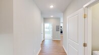 This single-story residence in Huntsville, Alabama presents a clean, contemporary design characterized by soft neutral tones, white trim, and an abundance of natural light throughout. The interior palette of light gray walls and white woodwork creates a cohesive, modern aesthetic from room to room.

The entry hallway, finished with smooth light-toned hardwood-style flooring and recessed lighting, connects the main living areas efficiently. The open-concept kitchen is a functional standout, featuring white shaker-style cabinetry, granite-look countertops, a peninsula with an undermount sink, and a full suite of stainless steel appliances including a refrigerator, range, and microwave. The kitchen flooring continues the warm hardwood-style finish seen throughout the main areas.

The living room benefits from multiple windows and a glass-paneled entry door with transom, flooding the space with natural light, while a ceiling fan adds comfort overhead.

Bedrooms are finished with plush neutral carpet and ceiling fans, each receiving natural light through blinded windows with exterior views.

The bathrooms are well-appointed, with one featuring a soaking tub with white subway tile surround, and another offering a glass-enclosed shower, both with granite-topped vanities and tile flooring.