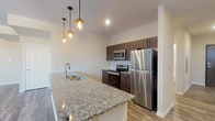 Located at 626 Lehman St in Columbus, Ohio, this single-floor residence offers a thoughtfully designed layout with modern finishes throughout. The open-concept living area is a standout feature, defined by a graceful curved wall lined with multiple windows that invite an abundance of natural light and provide neighborhood views. Wood-look plank flooring flows throughout the main living spaces, complemented by a ceiling fan and recessed lighting.

The kitchen is well-appointed with rich dark-toned cabinetry, granite countertops, a tile backsplash, and a full suite of stainless steel appliances including a refrigerator, electric range, and over-the-range microwave. A peninsula with an undermount sink and pendant lighting overhead creates a functional and stylish divide between the kitchen and living area.

The bedrooms are carpeted for comfort, with one featuring dual closets outfitted with wire shelving systems, while another includes a spacious walk-in closet with multi-level wire shelving for ample storage. The bathrooms mirror the kitchen's design aesthetic, each featuring granite-topped vanities with dark wood cabinetry and a tub/shower combination. Wood-look flooring carries through the bathrooms, tying the overall aesthetic of the unit together cohesively.