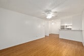 This single-story, one-bedroom, one-bathroom unit offers a well-organized layout across a compact but efficiently utilized floor plan. Hardwood-style flooring runs consistently throughout all rooms, providing a cohesive aesthetic and easy maintenance.

The living room is a comfortable, open space featuring a ceiling fan with light fixture, neutral white walls, and a large window dressed with vertical blinds that frame views of surrounding greenery. A wall-unit air conditioner provides climate control. The room offers a clean, versatile space for various furniture arrangements.

The kitchen is functionally equipped with stainless steel appliances, including a full-size refrigerator and electric range. White cabinetry extends to the ceiling, maximizing storage capacity, while a granite-style countertop adds a polished touch. A ceiling fan is positioned in the adjacent dining area.

The bedroom is a well-proportioned room featuring hardwood-style flooring, a ceiling fan, a window with vertical blinds offering outdoor views, and a mirrored sliding closet that enhances the sense of space while providing practical storage.

The bathroom includes a white vanity with a granite-style countertop, a medicine cabinet with mirror, and a separate water closet with a combination tub and shower. Chrome fixtures and white cabinetry maintain a clean, uniform finish throughout.