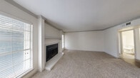 Located at 100 Hollow Tree Ln in Houston, TX, this single-story, one-bedroom, one-bathroom residence offers a well-organized layout across a comfortable footprint. The open-concept living room serves as the heart of the home, featuring a classic wood-burning fireplace with a raised hearth and a painted mantel, crown molding along the ceiling, and multiple windows fitted with blinds that allow natural light to fill the carpeted space. A pass-through window connects the living area to the kitchen, which is equipped with white cabinetry, light countertops, a tile backsplash, wood-look flooring, and black appliances including a full-size refrigerator and electric range. An adjacent pantry provides additional storage. The bedroom offers generous space, plush carpet, a ceiling fan with light fixture, a window with outdoor views, and direct access to a dedicated walk-in closet. The full bathroom includes a tub-shower combination and a marble-top vanity. A hallway connects the private areas of the home to the main living spaces. The neutral color palette throughout creates a clean, cohesive atmosphere suited to a variety of interior styles.