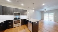 Located at 634 E Walnut Lawn St in Springfield, MO, this well-appointed one-bedroom, one-bathroom unit is thoughtfully designed across a single floor. The open-concept layout seamlessly connects the kitchen and living room, creating an inviting and functional living space. The kitchen is a standout feature, showcasing dark espresso cabinetry with modern hardware, a classic white subway tile backsplash, granite countertops on the peninsula island, and a full suite of stainless steel appliances including a range, microwave, dishwasher, and refrigerator. Stylish pendant lighting illuminates the island, while recessed lighting brightens the entire area. Light hardwood flooring flows throughout the main living areas, adding warmth and continuity. The living room benefits from natural light through a sliding glass door that opens to a balcony. The bedroom features plush carpeting, a ceiling fan, and a window with outdoor views. A dedicated walk-in closet with wire shelving provides ample storage. The bathroom is finished with neutral large-format tile flooring. Additional conveniences include a dedicated laundry area and utility room, rounding out this efficiently designed and modern home.