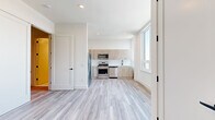 Located at 55 Washington St in East Orange, NJ, this thoughtfully designed 1-bedroom, 2-bathroom unit offers a clean, contemporary aesthetic throughout. Light-toned luxury vinyl plank flooring flows seamlessly across the entire single-floor layout, complementing the bright white walls and recessed lighting that give the space an airy, modern feel.

The open-concept living and kitchen area is a standout feature, anchored by large windows that flood the space with natural light and frame views of the surrounding cityscape. The kitchen is well-appointed with light wood-tone cabinetry extending to the upper walls for ample storage, stainless steel appliances including a gas range, microwave, dishwasher, and refrigerator, and a clean white countertop with a matte black sink fixture.

The generously sized primary bedroom offers a quiet retreat with neutral walls and hardwood-style flooring. A dedicated in-unit laundry closet with a stacked washer and dryer adds everyday convenience. Both bathrooms are finished in a crisp, modern style featuring floating white vanities with gold hardware accents and mirrored medicine cabinets. The full bathroom includes a tiled tub-shower combination with gold trim detailing, while the second bathroom serves as a half-bath with terrazzo-style flooring.