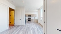 Located at 55 Washington St in East Orange, NJ, this thoughtfully designed 1-bedroom, 2-bathroom unit offers a clean, contemporary aesthetic throughout. Light-toned luxury vinyl plank flooring flows seamlessly across the entire single-floor layout, complementing the bright white walls and recessed lighting that give the space an airy, modern feel.

The open-concept living and kitchen area is a standout feature, anchored by large windows that flood the space with natural light and frame views of the surrounding cityscape. The kitchen is well-appointed with light wood-tone cabinetry extending to the upper walls for ample storage, stainless steel appliances including a gas range, microwave, dishwasher, and refrigerator, and a clean white countertop with a matte black sink fixture.

The generously sized primary bedroom offers a quiet retreat with neutral walls and hardwood-style flooring. A dedicated in-unit laundry closet with a stacked washer and dryer adds everyday convenience. Both bathrooms are finished in a crisp, modern style featuring floating white vanities with gold hardware accents and mirrored medicine cabinets. The full bathroom includes a tiled tub-shower combination with gold trim detailing, while the second bathroom serves as a half-bath with terrazzo-style flooring.