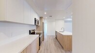 Located on S Sepulveda Blvd in West Los Angeles, this modern residence offers four bedrooms and four bathrooms across a thoughtfully designed single-floor layout. The open-concept kitchen and living area serves as the heart of the home, featuring a large central island with a white quartz countertop and undermount sink, two-tone cabinetry combining crisp white upper cabinets with warm wood-finish lower cabinets, and stainless steel appliances including a refrigerator, range, and microwave. Light wood-style flooring flows throughout the main living areas, enhancing the bright, airy ambiance created by recessed lighting. A stacked in-unit washer and dryer is conveniently tucked within the kitchen corridor. The living area opens to a private balcony through a glass door, inviting natural light and outdoor views. Each of the four bedrooms is finished with plush carpeting, recessed lighting, and generous closet space, with several rooms featuring large windows that bring in ample sunlight. The four bathrooms are clean and contemporary, each appointed with tiled tub-shower combinations with sliding glass doors, wood-toned vanities, and white quartz countertops. Three dedicated closets and a hallway complete this well-organized, modern Los Angeles residence.