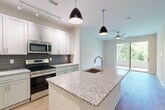 Located at 421 Broadway St in the heart of Asheville, NC, this thoughtfully designed one-bedroom, one-bathroom residence offers a modern living experience with high-quality finishes throughout. The open-concept layout maximizes the efficient use of space, creating a bright and airy atmosphere from the moment you enter.

The kitchen is a standout feature, boasting a large granite-topped island with an undermount sink and stylish pendant lighting overhead. White upper cabinetry is paired with sage-toned lower cabinets, complemented by a dark linear tile backsplash. Stainless steel appliances — including a refrigerator, range, and microwave — complete the contemporary look. Track lighting and light wood-style flooring add warmth and functionality throughout the main living area.

Sliding glass doors open to an outdoor space, allowing natural light to pour in and offering lush greenery views, enhanced by a ceiling fan that promotes comfortable airflow.

The bedroom is a calm, well-lit retreat with wide windows framing tree-lined views, a ceiling fan, and clean light wood flooring. Two closets provide ample storage. The bathroom features granite countertops, a framed mirror, and light-toned finishes that echo the home's cohesive, modern aesthetic. Light wood flooring flows seamlessly throughout the entire residence, tying each space together with understated elegance.