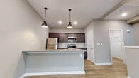This thoughtfully designed 3-floor space offers a cohesive blend of modern finishes and functional layouts throughout. Light hardwood flooring flows consistently across all levels, complementing the neutral gray-toned walls and crisp white trim that define the interior aesthetic.

The kitchen serves as a central highlight, featuring a substantial island with a granite countertop, undermount sink, and seating overhang. Dark-toned shaker-style cabinetry pairs with a white subway tile backsplash and a full suite of stainless steel appliances, including a refrigerator, electric range, and built-in microwave. Industrial-style pendant lights add character overhead.

The bathrooms are well-appointed with dark shaker vanities topped with granite countertops, large mirrors, and tile-surround walk-in showers. Light hardwood flooring continues into these spaces, maintaining a unified design language throughout.

The open living areas are generously proportioned and benefit from natural light through windows offering exterior views. Wall-mounted mini-split units provide climate control in the living spaces. A staircase with a wood handrail connects all three floors, with a convenient stacked washer and dryer unit tucked neatly into a dedicated laundry closet on one of the upper levels.