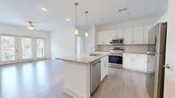 Located at 11310 Vandelay Ct in Charlotte, NC, this single-floor residence offers a clean, contemporary design throughout. The open-concept kitchen serves as the heart of the home, featuring a large central island with granite countertops, an undermount sink, and pendant lighting overhead. White shaker-style cabinetry, a tile backsplash, and a full suite of stainless steel appliances — including a range, microwave, refrigerator, and dishwasher — complete the well-appointed space. Light wood-style flooring extends through the main living areas, lending a bright and cohesive feel.

The living area opens to a private balcony through a set of French doors, allowing generous natural light to fill the space. Bedrooms are carpeted for comfort and equipped with ceiling fans and windows fitted with blinds. The primary bathroom offers a double-sink vanity with granite countertops, white cabinetry, and a soaking tub, while a secondary full bathroom mirrors the same refined finishes with a single vanity and tub-shower combination. Throughout the residence, a consistent palette of whites and neutrals creates a fresh, move-in-ready atmosphere ideal for modern living in Charlotte's vibrant 28277 corridor.