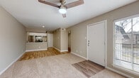 This single-floor residence offers a clean, functional layout designed for comfortable everyday living. The open-concept living area greets you upon entry, featuring warm neutral tones on the walls, plush wall-to-wall carpeting, and wood-look laminate flooring that defines the entryway and kitchen zones. A ceiling fan overhead provides year-round comfort in the main living space, which flows seamlessly into the kitchen. The kitchen is well-equipped with white shaker-style cabinetry, granite-look countertops, a peninsula with bar seating, and a full suite of stainless steel appliances including a refrigerator and a gas range. A textured ceiling adds a classic touch throughout the home. The bedrooms are generously sized, each finished with soft carpeting, ceiling fans, and neutral beige walls that create a calm and restful atmosphere. One bedroom benefits from a large window fitted with horizontal blinds, allowing ample natural light to fill the room. The overall ambiance of the space is bright, clean, and move-in ready, with a consistent neutral color palette that provides a versatile backdrop for a variety of interior styles. The practical floor plan makes efficient use of space while maintaining an open and airy feel.