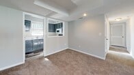 This single-story residence is thoughtfully laid out across a well-connected floor plan, offering a comfortable and functional living environment throughout. The living room serves as a central gathering space, finished with plush wall-to-wall carpeting, neutral gray walls, and a textured ceiling. A ceiling fan with an integrated light fixture provides both comfort and illumination, while a full-width sliding glass door fitted with vertical blinds opens to a balcony, allowing natural light to fill the room. A wall-mounted thermostat adds convenience nearby.

Adjacent to the living room, a carpeted dining area connects directly to the kitchen through a pass-through window, maintaining an open and communicative flow between spaces. The kitchen features gray cabinetry with decorative hardware, white countertops, a double stainless steel sink, hardwood-style flooring, and white appliances including a range, microwave, and dishwasher. A window above the sink brings in additional natural light.

The bedrooms are carpeted and tranquil, with one offering access to a spacious walk-in closet equipped with wire shelving and hanging rods. Both bathrooms are finished with white tile flooring, gray vanity cabinetry, white countertops, and natural light from privacy-screened windows.