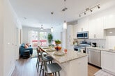 Located at 9113 Baltimore Ave in College Park, MD, this well-appointed 2-bedroom, 2-bathroom residence offers a thoughtfully designed single-floor layout. The open-concept living area seamlessly connects the kitchen, dining, and living spaces, creating an inviting and functional environment. The kitchen is outfitted with stainless steel appliances, white shaker cabinetry with modern hardware, a subway tile backsplash, and a granite-topped island with bar seating — ideal for both cooking and casual dining. Track and pendant lighting add a contemporary touch overhead. The living room features warm hardwood-style flooring, a ceiling fan, and large sliding glass doors that open onto a private balcony overlooking the surrounding streetscape. Each bedroom is comfortably proportioned, with plush carpeting, ceiling fans, and windows that invite natural light. The primary bedroom connects to a walk-in closet with wire shelving and an en-suite bathroom featuring a glass-enclosed shower, granite vanity, white cabinetry, and light tile flooring. The second bathroom is equally well-finished. Additional highlights include multiple closets, a dedicated laundry area, and a utility room, ensuring practical storage throughout.