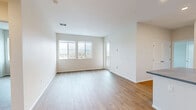 Located at 17445 Bollinger Canyon Rd in San Ramon, CA, this well-designed one-bedroom, one-bathroom residence offers a clean, modern aesthetic throughout its efficiently laid-out single floor. The open-concept kitchen and living area serves as the heart of the home, anchored by a substantial center island with a dark stone countertop and white shaker-style cabinetry featuring brushed gold hardware. The kitchen is outfitted with stainless steel appliances, including a range, over-the-range microwave, and refrigerator, all complemented by a classic white subway tile backsplash. Warm-toned wood-look flooring flows seamlessly through the living, kitchen, and hallway areas, lending a cohesive and inviting feel. A door off the kitchen leads to a private balcony with open views of the surrounding landscape. The spacious living room is bright and airy, with multiple windows drawing in natural light and offering scenic views of the hills. The bedroom is a comfortable retreat with its own large window framing outdoor views, while the walk-in closet provides generous wire-shelved storage. The bathroom features a full soaking tub and shower combination with built-in shelving, finished in crisp white tones with brushed nickel fixtures.