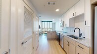 This efficiently designed one-bedroom, one-bathroom unit at 101 Church Ave in College Station, Texas offers a thoughtfully laid-out single-floor living space. Light wood-tone flooring runs throughout, creating a warm and cohesive aesthetic across every room.

The kitchen is a standout feature, equipped with a full suite of stainless steel appliances including a refrigerator, range, dishwasher, and over-the-range microwave. White cabinetry extends to the ceiling for ample storage, complemented by granite countertops and a classic tile backsplash. A deep single-basin sink with a modern matte black faucet adds a contemporary touch. The kitchen flows openly toward the living area, where floor-to-ceiling windows flood the space with natural light and offer expansive views of the College Station skyline.

The bedroom is a cozy, private retreat with its own large window framing bright outdoor views, light-toned walls, and warm flooring that continues from the main living areas.

The bathroom is clean and modern, featuring a walk-in glass-enclosed shower with vertically tiled walls, a white vanity with granite countertop, and matching light wood flooring. The overall design throughout the unit is contemporary and minimalist, prioritizing functionality and natural light.