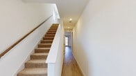Located on Garland Road in Dallas, TX, this two-story home offers three bedrooms and three bathrooms across a thoughtfully designed layout. The main level opens into a combined kitchen and living area with light wood-look flooring and abundant natural light from large windows and a glass door leading to the outdoors. The kitchen is a standout feature, boasting a generous island with a white quartz countertop, an undermount sink, light wood cabinetry with gold hardware, stainless steel appliances, and pendant lighting overhead. The upper level hosts the bedrooms, all carpeted and well-lit by wide windows with outdoor views. The spacious primary bedroom includes its own closet with built-in shelving and hanging rods. The bathrooms are finished with large-format marble-style tile on both the floors and tub surrounds, paired with warm wood vanities and wide mirrors. A dedicated laundry area includes a full-size washer and dryer. Connecting the floors is a carpeted staircase alongside a wood-floored hallway with recessed lighting. The attached garage features an automatic opener and ample storage space. Two closets and a second hallway round out the functional layout of this well-appointed Dallas home.