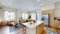 Located in Miami's Westchester neighborhood, this well-designed 2-bedroom, 2-bathroom residence offers a thoughtfully organized single-floor layout. The open-concept living, dining, and kitchen area serves as the heart of the home, bathed in natural light from large windows and a sliding glass door that opens to a balcony with outdoor views. The kitchen is outfitted with stainless steel appliances, a blue tile backsplash, a mix of white upper and warm wood lower cabinetry, open shelving, and a central island with seating — ideal for both cooking and casual dining. The adjoining dining area features sheer draping curtains and balcony access, while the living room offers a ceiling fan and a warm, earthy aesthetic. Both bedrooms are serene retreats, each featuring a striking blue accent wall, natural light, and direct access to closets. The primary bedroom includes a dedicated walk-in closet with built-in shelving. The bathrooms are clean and modern, with the full bath showcasing a frameless glass walk-in shower, wood-tone vanity, and light tile flooring. Light hardwood flooring flows throughout the entire residence, complemented by recessed lighting and a neutral warm color palette. The unit also includes an in-unit laundry and five closets for exceptional storage.