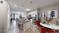 This thoughtfully designed single-floor residence offers a seamless open-concept layout that connects the kitchen, dining, and living areas into one cohesive and functional space. The kitchen serves as the heart of the home, anchored by a generous granite-topped island with bar seating and pendant lighting overhead. White shaker cabinetry pairs elegantly with a full suite of stainless steel appliances, including a refrigerator, range, and microwave. Light wood-style plank flooring flows throughout the main living areas, enhancing the bright, airy ambiance.

The living room is comfortably proportioned, featuring large windows that invite natural light and offer views to the outdoors. A separate dining nook provides additional space for entertaining, complemented by stylish gold-accented décor details.

The two bedrooms are carpeted for comfort and include ceiling fans, plantation-style blinds, and ample natural light. Each room offers a calm, restful retreat with neutral tones and generous proportions.

The bathroom is finished with a granite-topped vanity with white cabinetry, wood-style tile flooring, and a clean, neutral color palette. Throughout the residence, consistent use of soft grays, whites, and warm wood tones creates a cohesive, modern aesthetic that is both welcoming and refined.