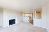 Located in Lynnwood, Washington, this well-appointed one-bedroom, one-bathroom residence offers a comfortable and functional layout across a single floor. The open-concept living and kitchen area serves as the heart of the home, where plush carpeting and neutral tones create a warm, inviting atmosphere. A white-tiled fireplace anchors the living room, while sliding glass doors lead to a private balcony with tree-lined outdoor views, filling the space with natural light. The kitchen is efficiently designed with white cabinetry, white appliances including a range, microwave, and refrigerator, and sleek marble-style countertops that extend to a peninsula overlooking the living area. Light wood-look flooring ties the kitchen together seamlessly. The bedroom is generously proportioned, featuring soft carpet, a window with outdoor views, and access to a spacious walk-in closet. The bathroom is clean and modern, offering a tub-shower combination, a white vanity with marble-style countertop, and wood-look tile flooring. A dedicated utility room houses a stacked washer and dryer, adding everyday convenience. Throughout, the residence maintains a cohesive, neutral palette that is move-in ready and easy to personalize.