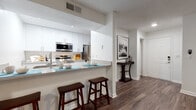 Located at 101 S Old Coachman Rd in Clearwater, Florida, this single-floor residence offers a cohesive and well-designed layout with a consistent aesthetic throughout. Rich, dark hardwood-style flooring flows seamlessly across the main living areas, providing a warm and polished foundation for the entire space.

The open-concept kitchen is a standout feature, outfitted with crisp white cabinetry, light quartz-style countertops, and a full suite of stainless steel appliances including a microwave, range, and refrigerator. A peninsula with bar seating connects the kitchen to the main living area, making it well-suited for casual dining and entertaining.

The living room is bright and inviting, with large windows that allow natural light to filter in and offer views of the surrounding greenery. A ceiling fan adds comfort, and the layout provides ample space for relaxed living. Adjacent to the living area, a dedicated dining nook with its own window creates a defined space for meals.

The bedrooms are comfortably sized, each featuring ceiling fans, natural light from well-positioned windows, and continued hardwood-style flooring. The bathroom is finished in a clean, all-white palette with a tub-shower combination, white vanity cabinetry, and dark flooring that ties back to the rest of the home. The overall ambiance is modern, bright, and functional.