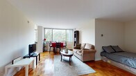 Situated at 2112 New Hampshire Avenue in Washington, D.C., this single-floor residence offers a thoughtfully designed layout that balances comfort and functionality. The open living and dining area serves as the heart of the home, featuring warm parquet hardwood flooring that adds timeless character throughout. A large picture window floods the space with natural light while framing lush green tree views, creating a bright and inviting atmosphere. The living area provides ample room for relaxed seating, while the adjacent dining space comfortably accommodates a dining set, making it ideal for everyday meals or entertaining.

The kitchen is efficiently designed with rich cherry wood cabinetry, dark granite countertops, tile flooring, and stainless steel appliances including a full-size refrigerator and dishwasher. The clean, practical layout maximizes functionality within the space.

The bathroom continues the design consistency found throughout the home, featuring matching cherry wood cabinetry topped with dark granite, a large vanity mirror, tile flooring, and a combined shower and closet area that offers convenient storage.

Overall, the residence presents a cohesive aesthetic with neutral wall tones, consistent finishes, and well-placed natural light, creating a comfortable and functional living environment in a prime Washington, D.C. location.